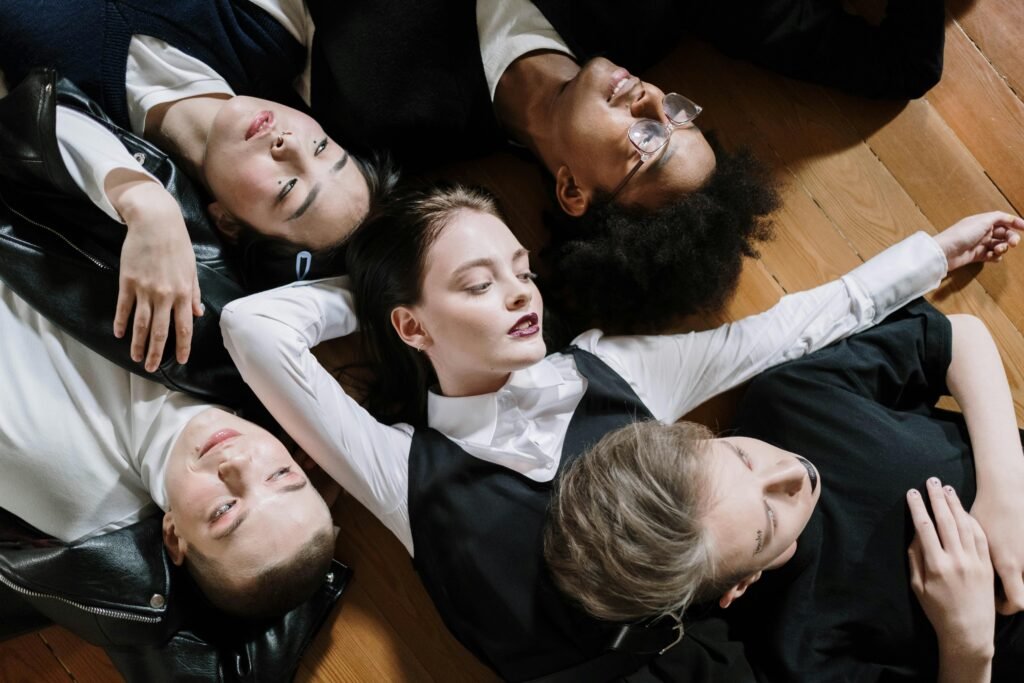 A diverse group of models lies together on a wooden floor, showcasing unity and fashion.