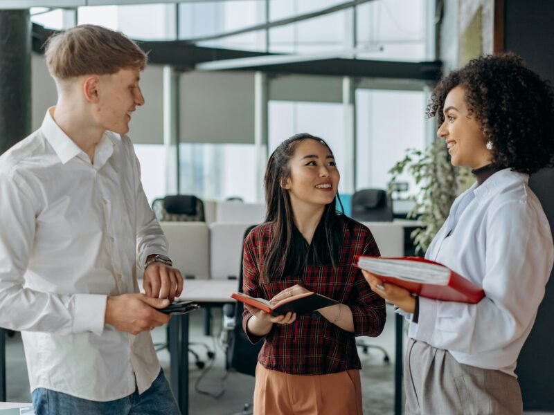A group of cheerful coworkers discussing a project in a bright, modern office setting.