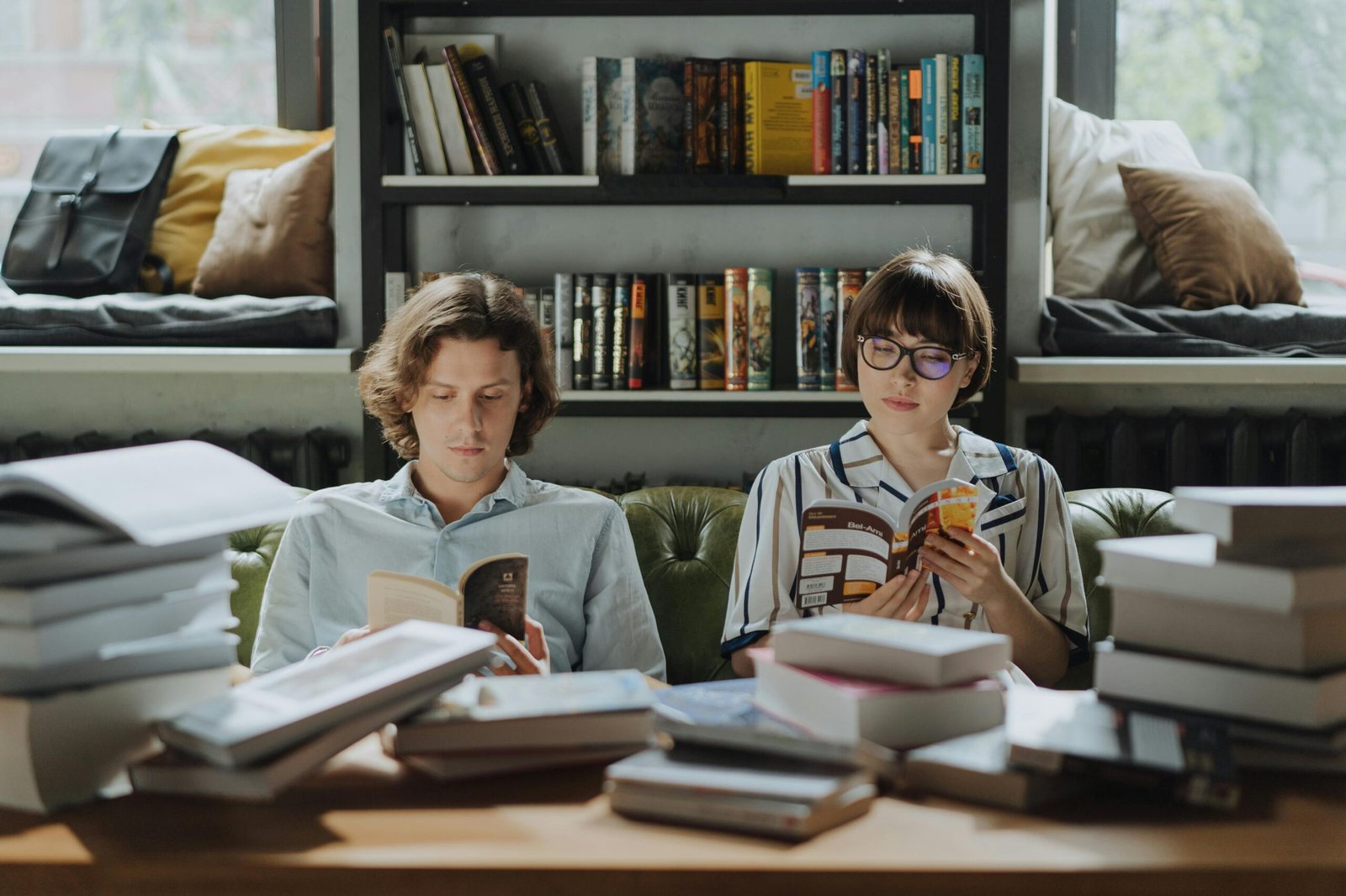 Two people enjoying a peaceful reading session surrounded by books in a cozy library atmosphere.