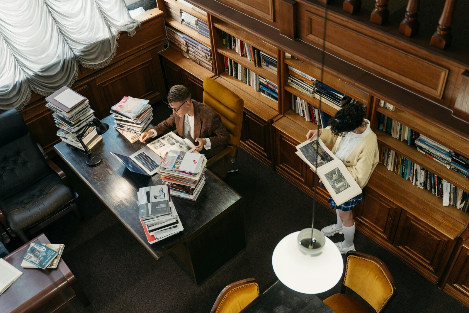 Aerial view of individuals reading and working in a cozy, wooden-themed library setting.