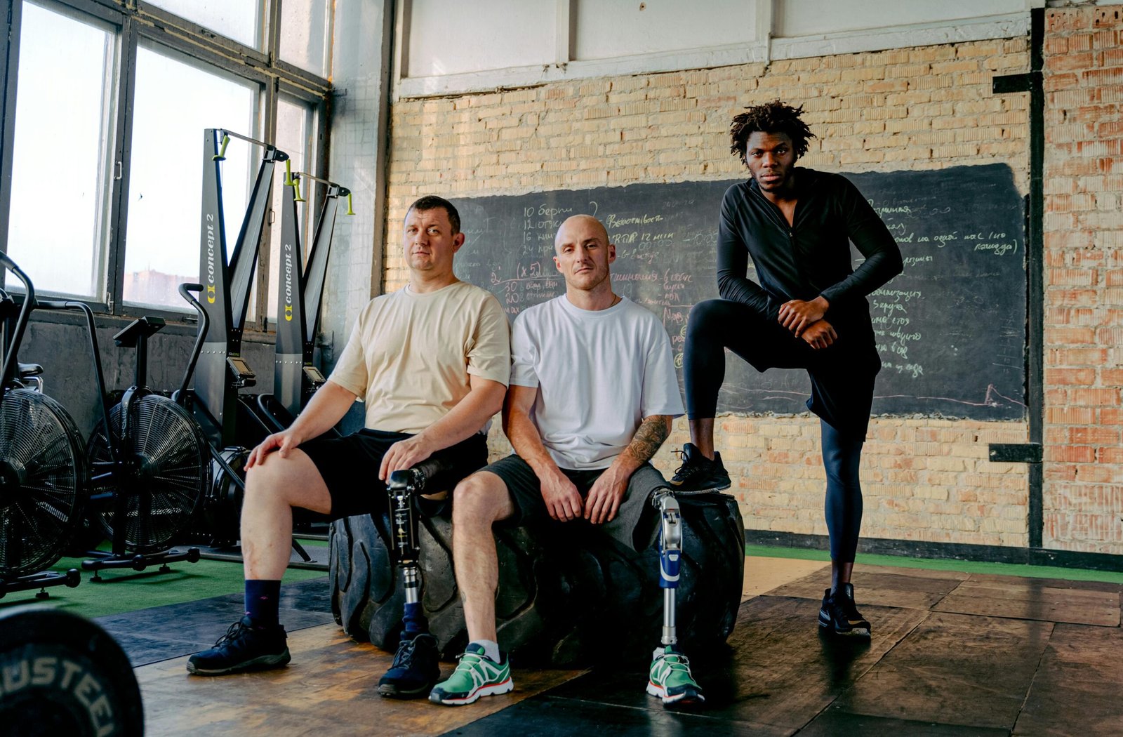 Diverse group of men with prosthetic legs posing confidently in a gym setting, showcasing strength and inclusivity.