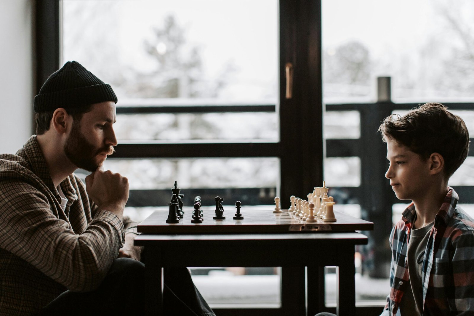 Father and son focused on a chess match indoors, highlighting bonding and strategy.