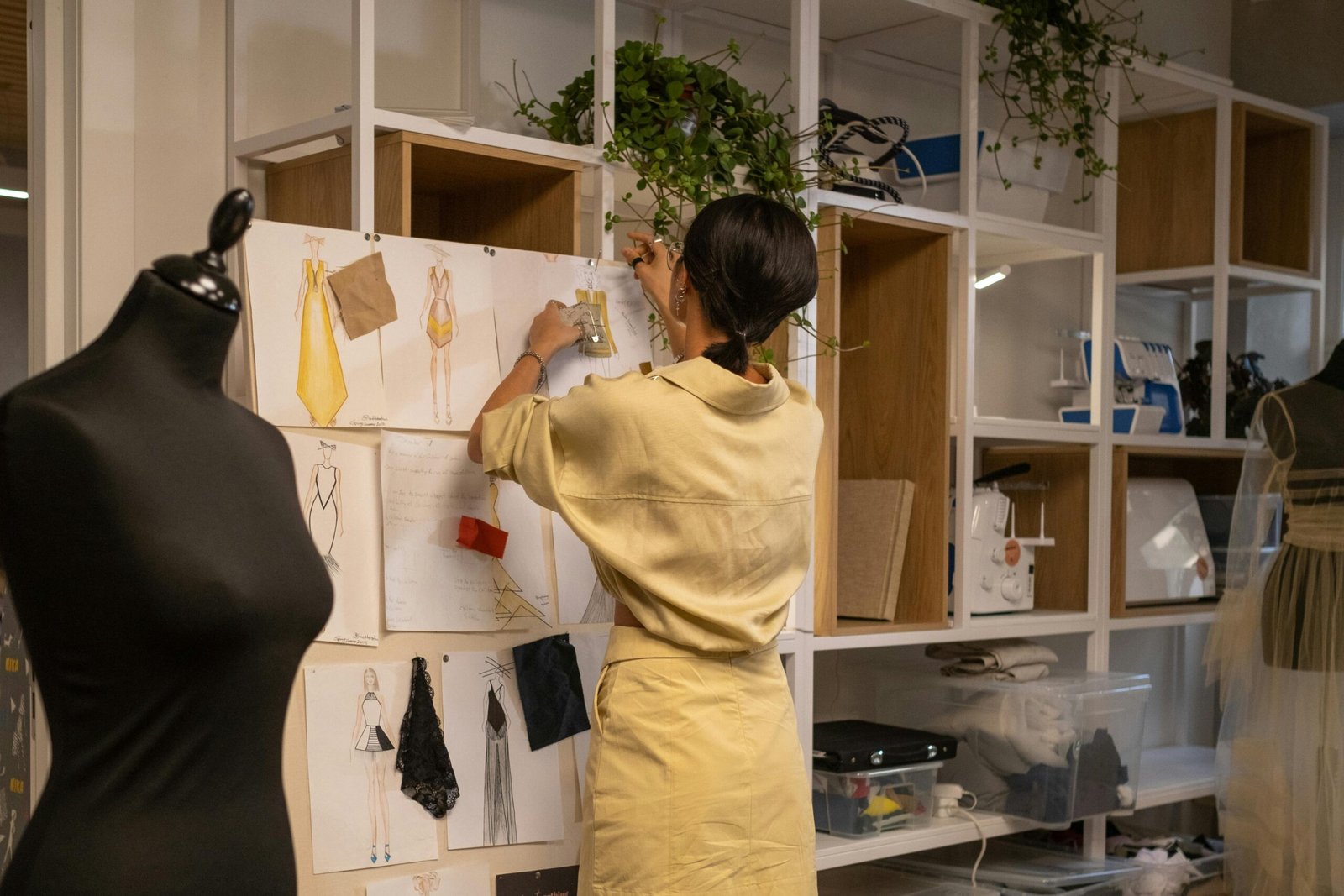 A fashion designer arranging a mood board in her workshop with sketches and fabric samples.