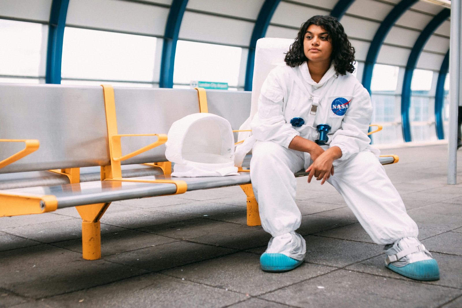 Woman in a NASA space suit sitting at a modern station, symbolizing exploration and future.