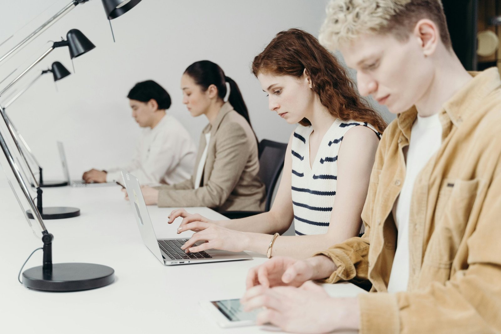 Diverse group of professionals working on laptops at a bright office workstation.