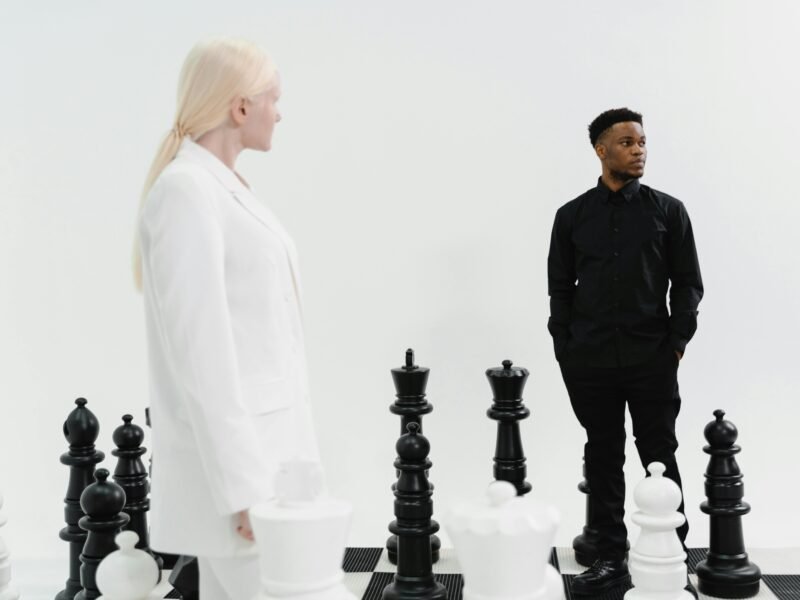Two individuals strategize in a life-sized chess game, emphasizing competition and strategy.