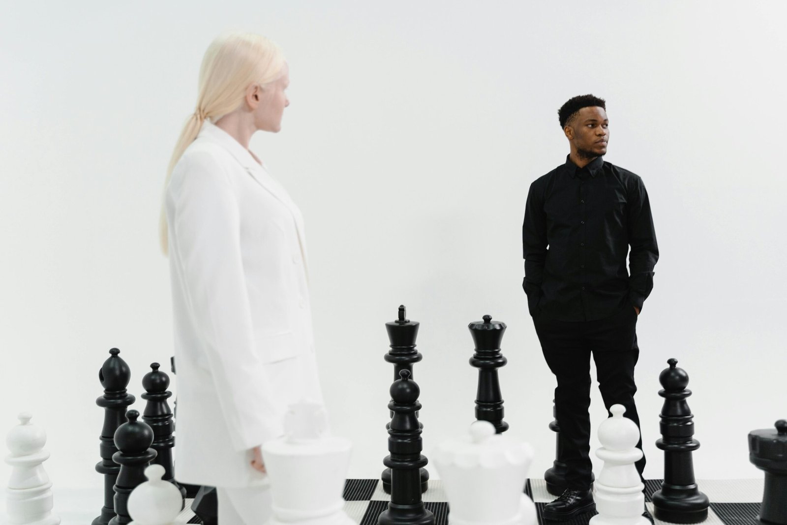 Two individuals strategize in a life-sized chess game, emphasizing competition and strategy.