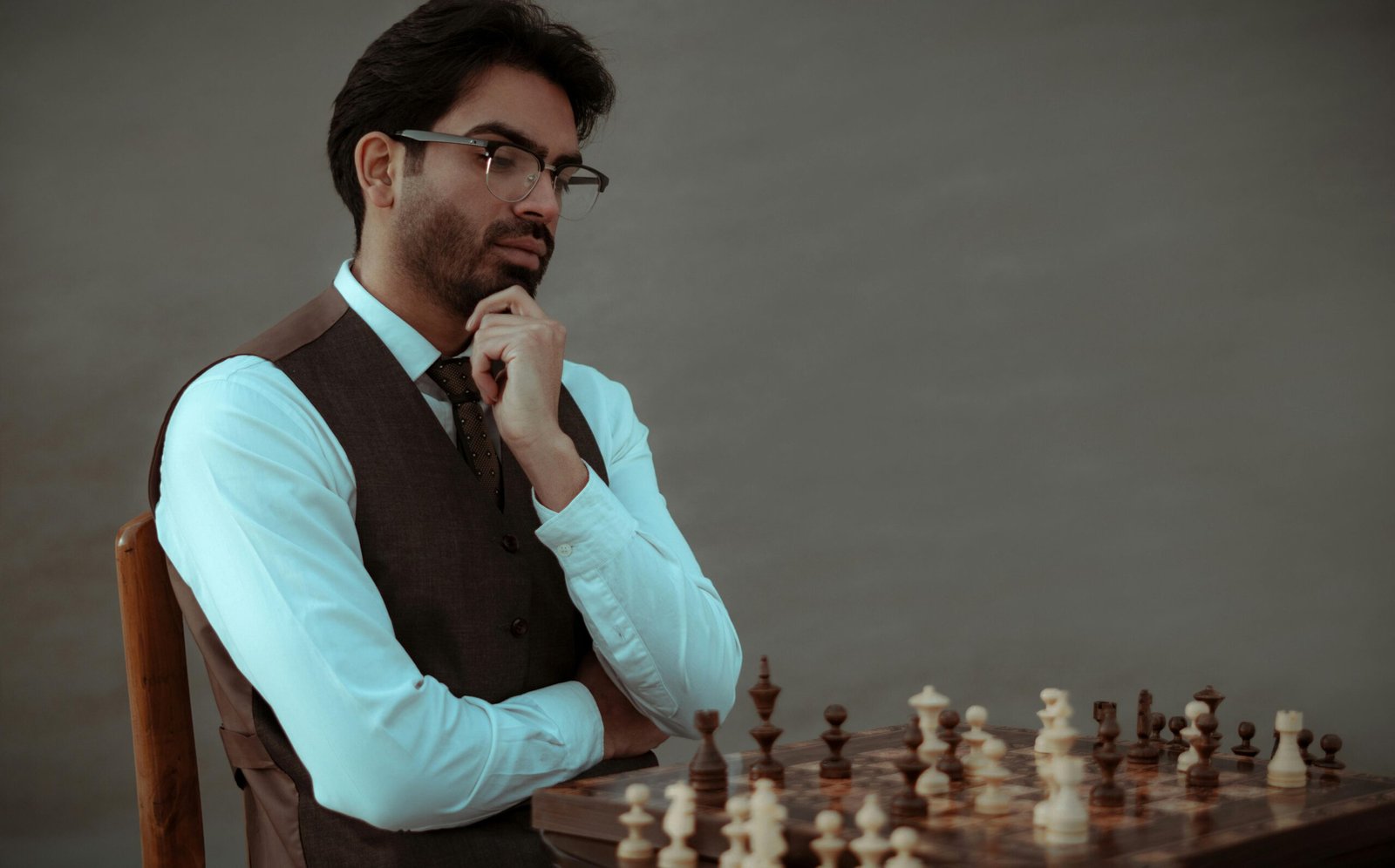 A man in formal attire deeply contemplating his next move in a chess game.
